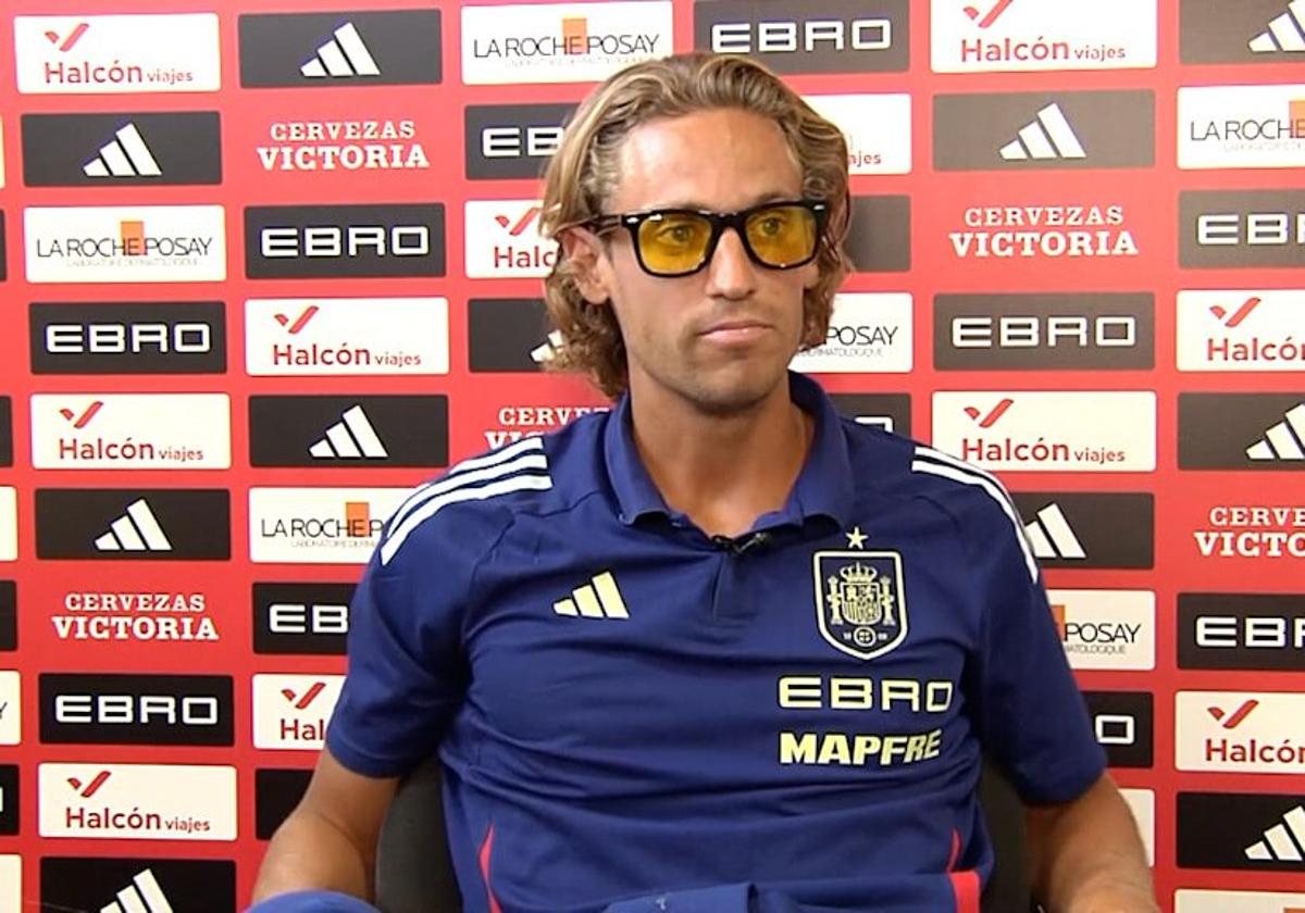 Marcos Llorente speaks to the media wearing yellow-tinted glasses.